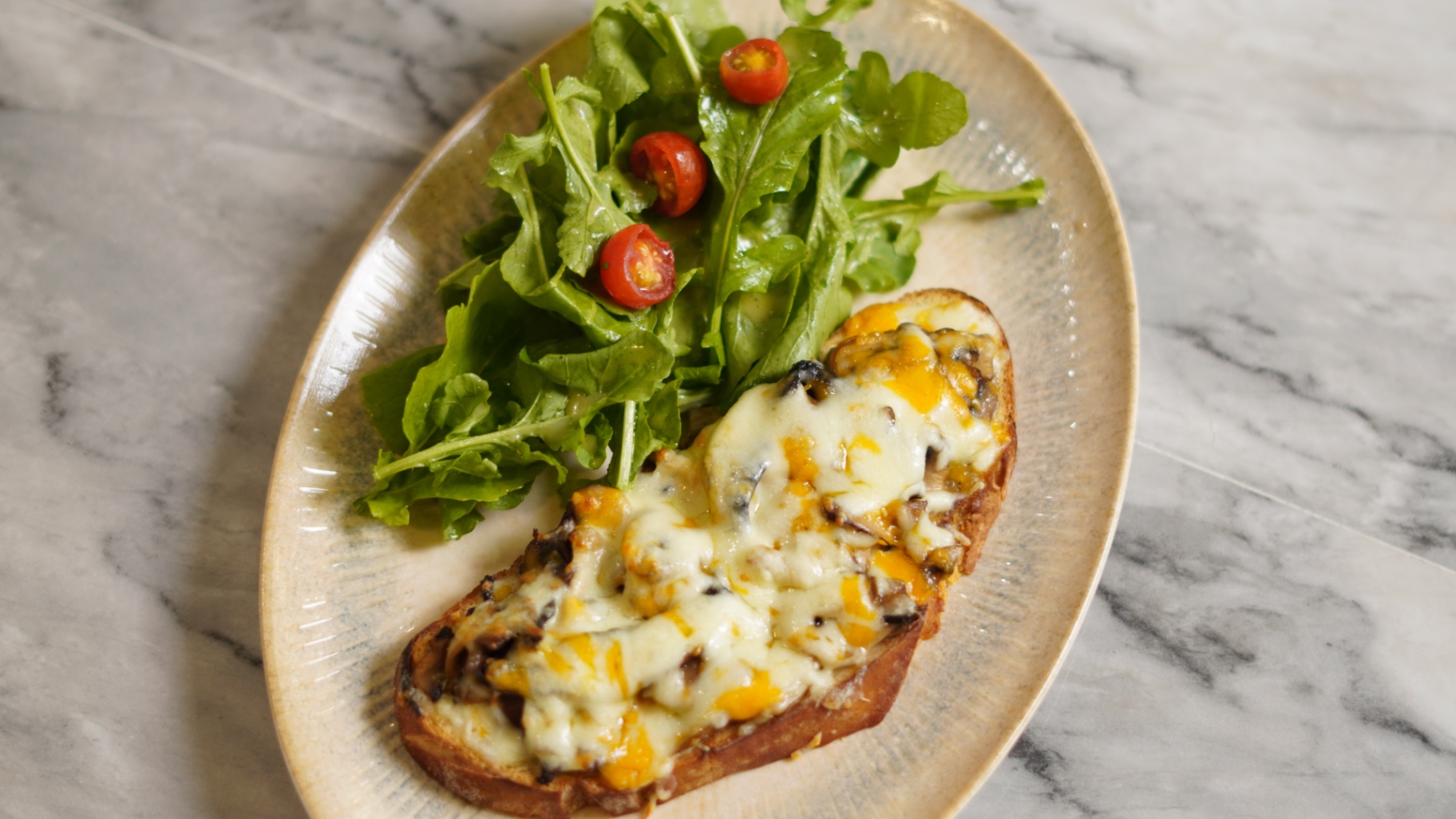 Mushroom melt on sourdough with melted cheese and a rocket salad