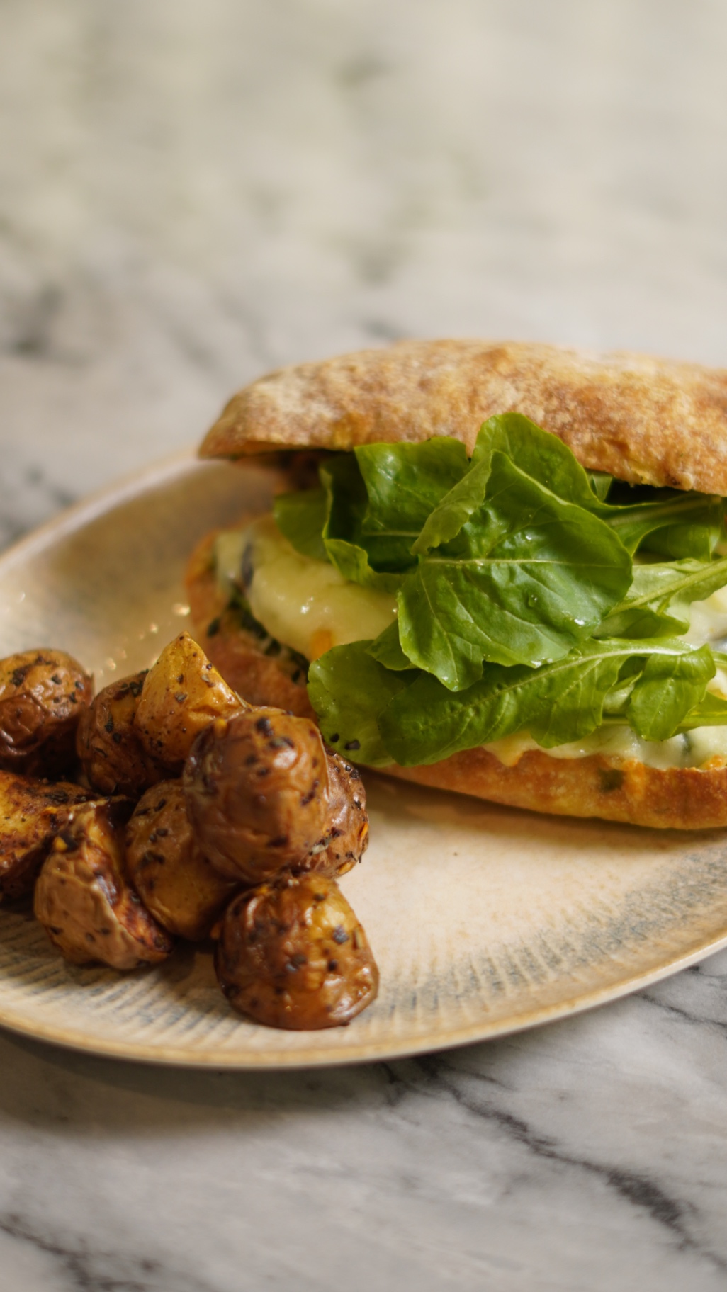 Ciabatta panini with melted cheese and rocket, served with roasted baby potatoes
